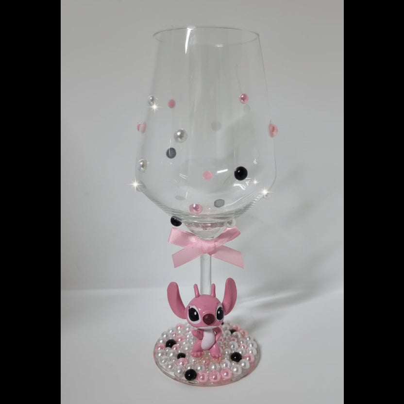 Decorative wine glass with pink character design on a white background