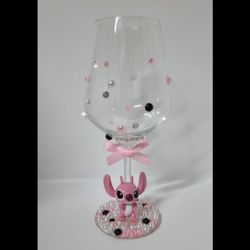 Decorative wine glass with pink character design on a white background