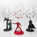 Decorative wine glasses with figurines on a white surface