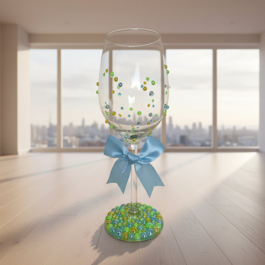 Decorative wine glass with colorful beads and a blue ribbon.