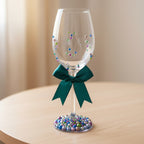 Decorative wine glass with colorful beads and a green ribbon.