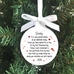 A round white Christmas ornament with a white ribbon bow, featuring a sentimental poem for 'Daddy' in black script and print, decorated with small red hearts and gold stars, hanging against a green pine tree background.
