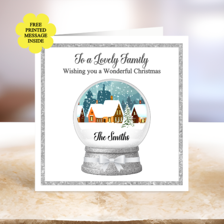 Personalised Christmas Card. The card has a silver glitter border, a snow globe illustration with a winter village scene, and the text 'To a Lovely Family Wishing you a Wonderful Christmas' and 'The Smiths.